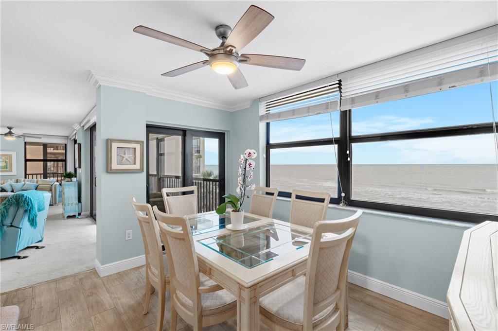 Dining room with ceiling fan, light wood-style flooring, crown molding, and a water view