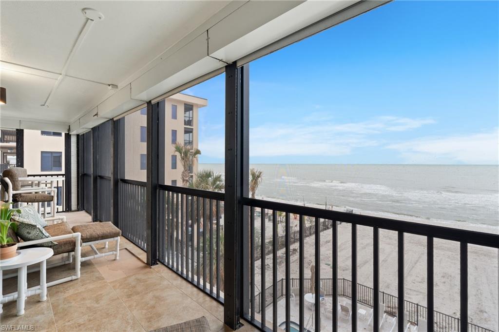 Balcony featuring view of water and beach and a sunroom