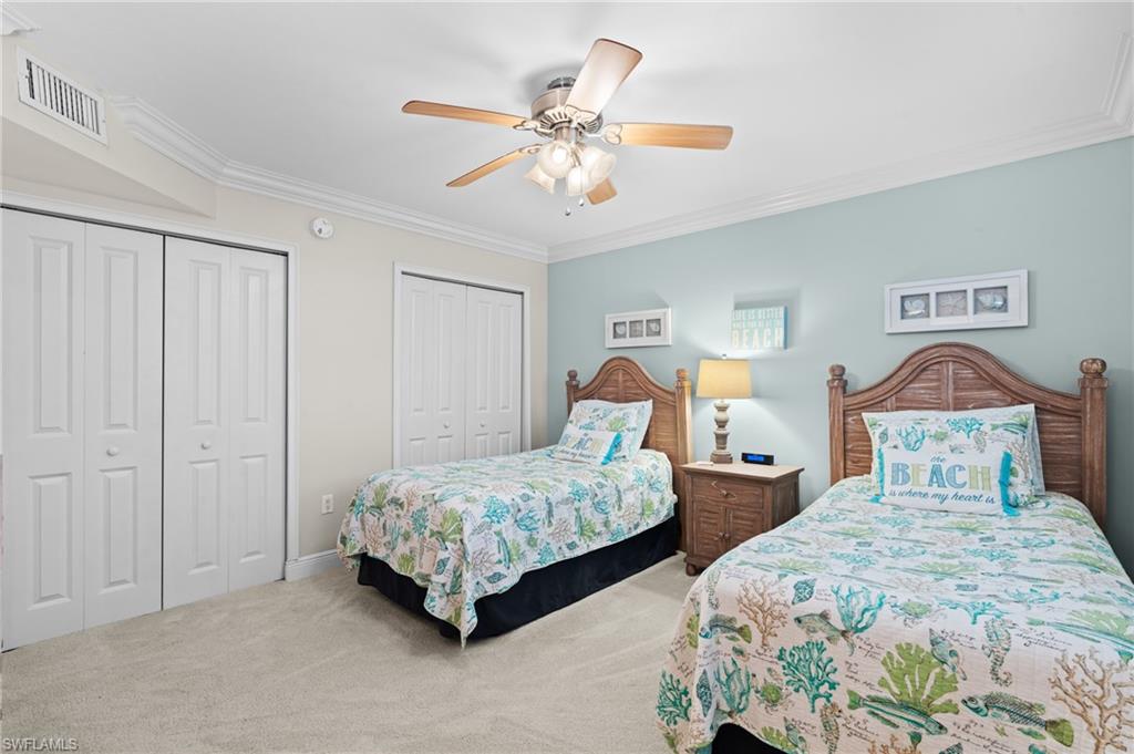 Bedroom with two closets, crown molding, carpet floors, and a ceiling fan