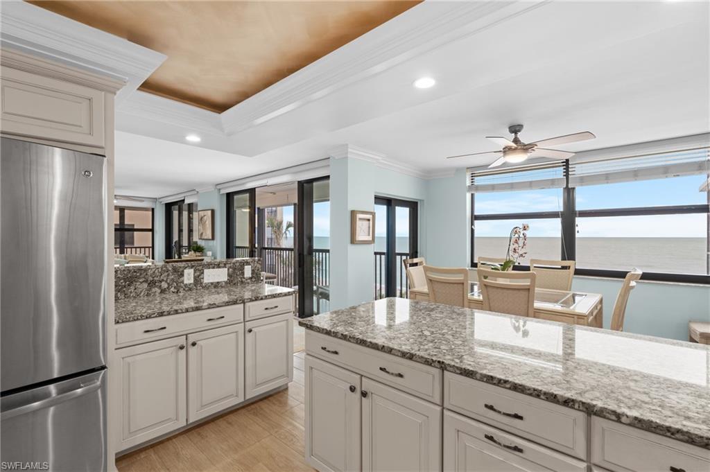 Kitchen featuring ornamental molding, freestanding refrigerator, light stone counters, recessed lighting, and ceiling fan