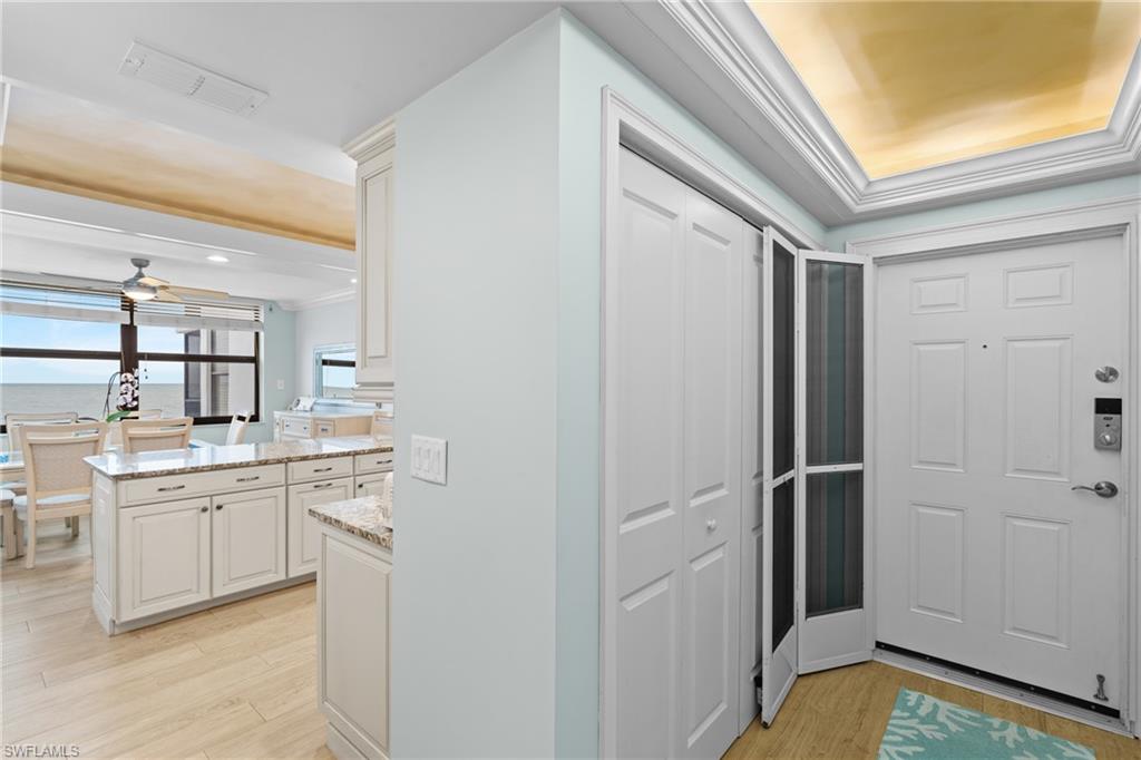 Entryway with crown molding, light wood-style flooring, a raised ceiling, and a ceiling fan