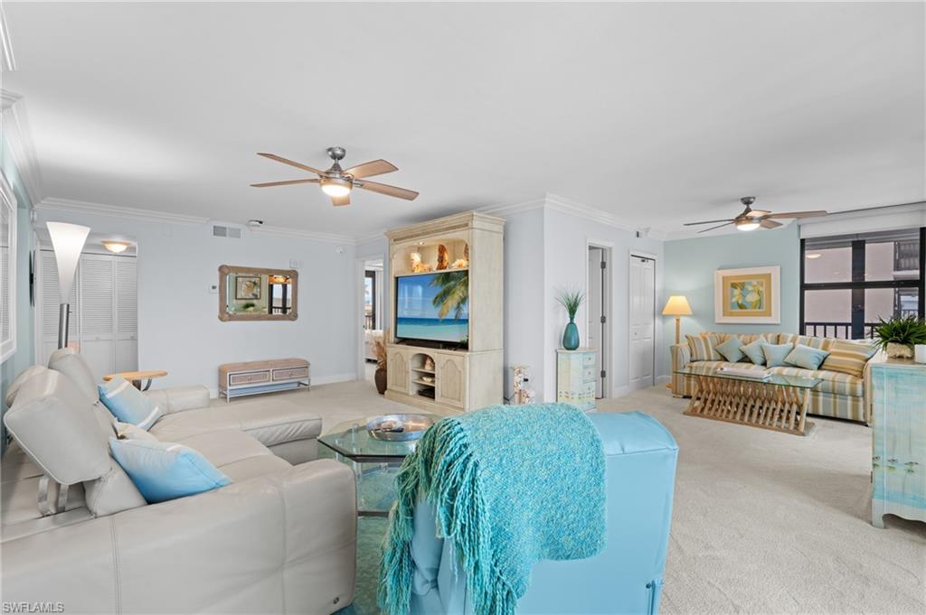 Living room with ceiling fan, crown molding, and light colored carpet