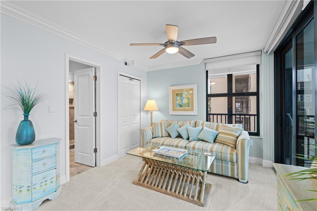 Living room with a ceiling fan, light colored carpet, and ornamental molding