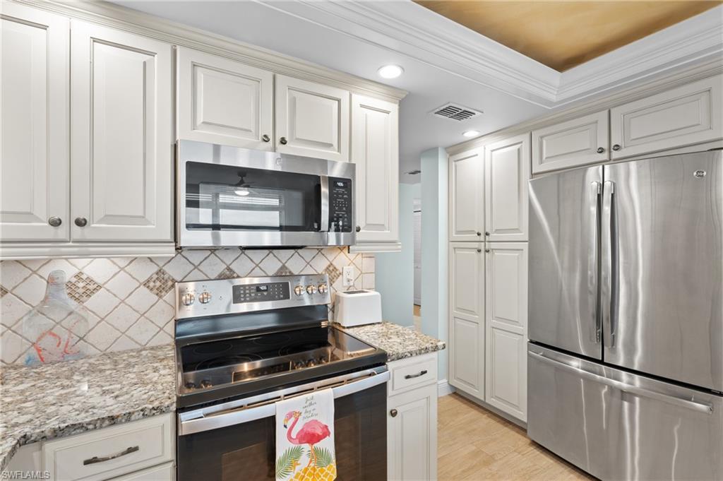 Kitchen with stainless steel appliances, backsplash, light wood-type flooring, recessed lighting, and light stone countertops