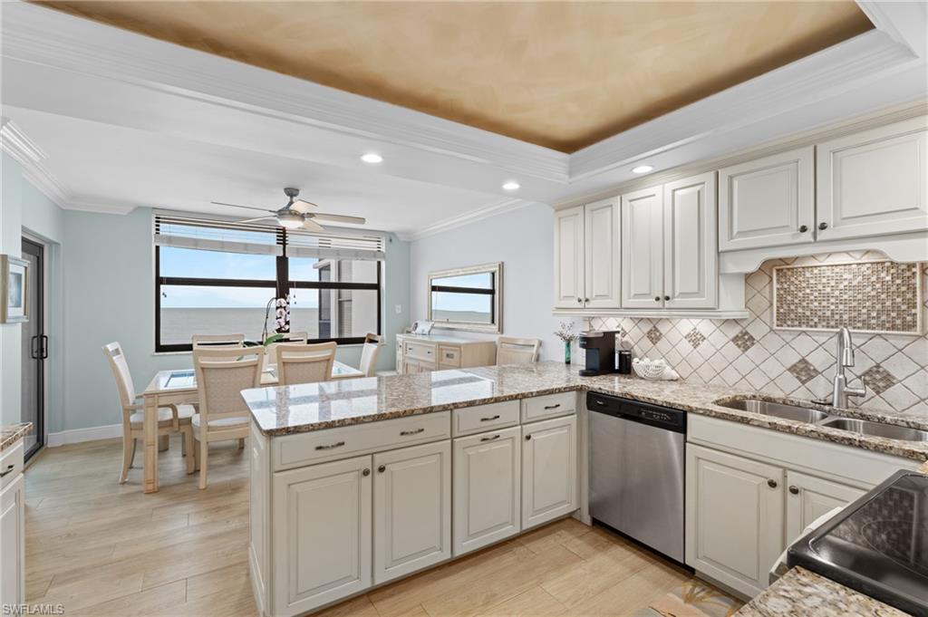 Kitchen with crown molding, decorative backsplash, stainless steel dishwasher, a peninsula, and light wood finished floors