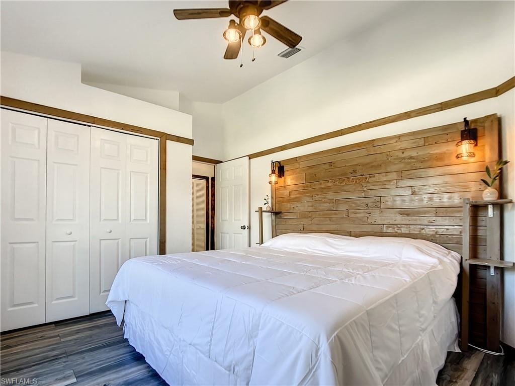 Bedroom featuring dark wood-style floors, a ceiling fan, a closet, and wood walls