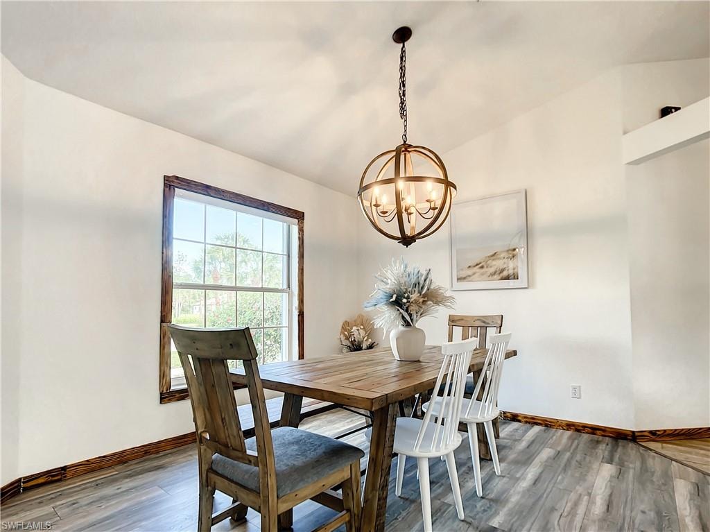Dining room featuring vaulted ceiling, light wood finished floors, and suspended lighting