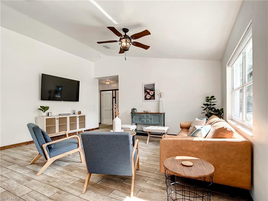 Living room with vaulted ceiling, wood finished floors, and a ceiling fan