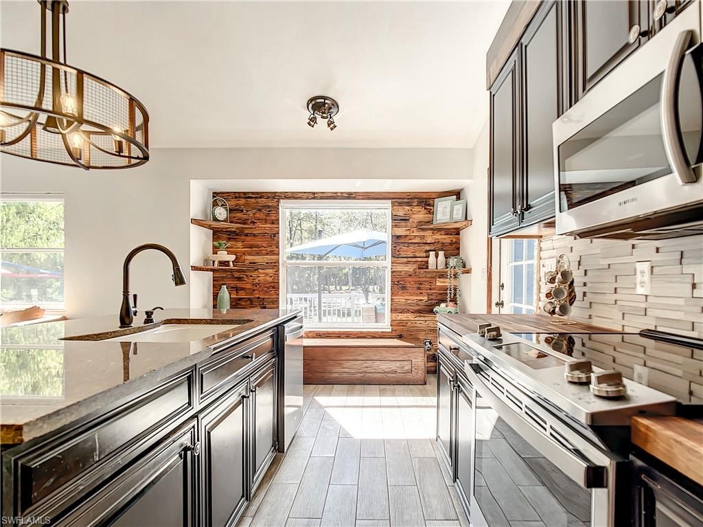 Kitchen featuring stainless steel appliances, butcher block countertops, backsplash, and a chandelier