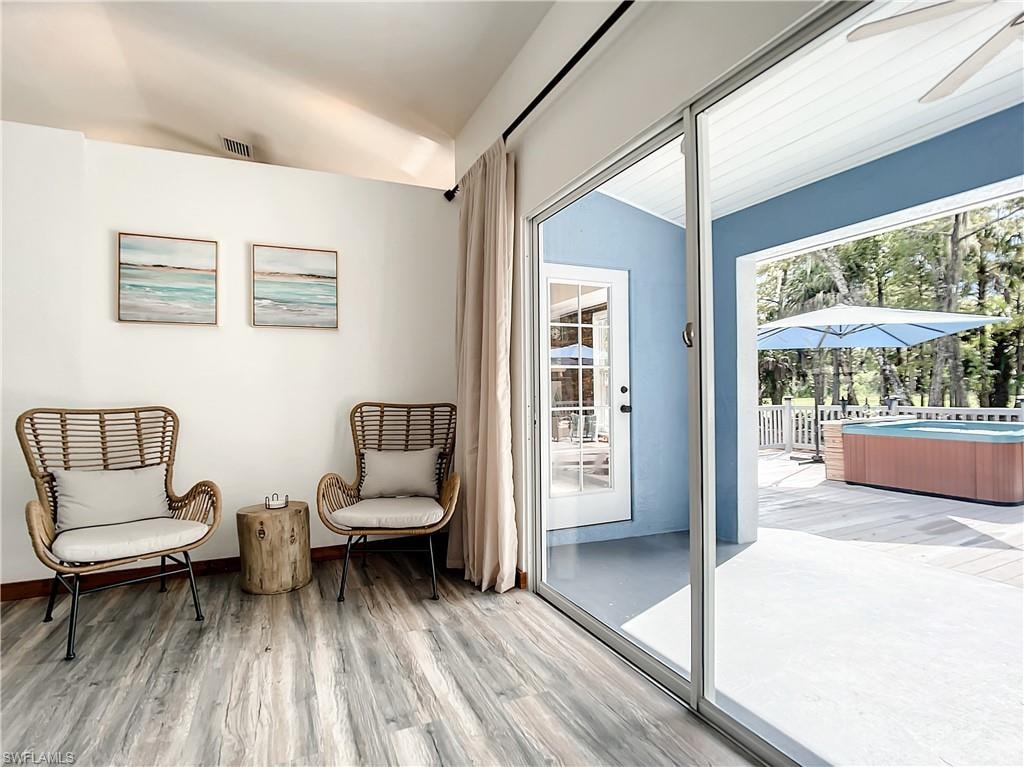 Living area featuring a sunroom, vaulted ceiling, light wood-type flooring, and a ceiling fan