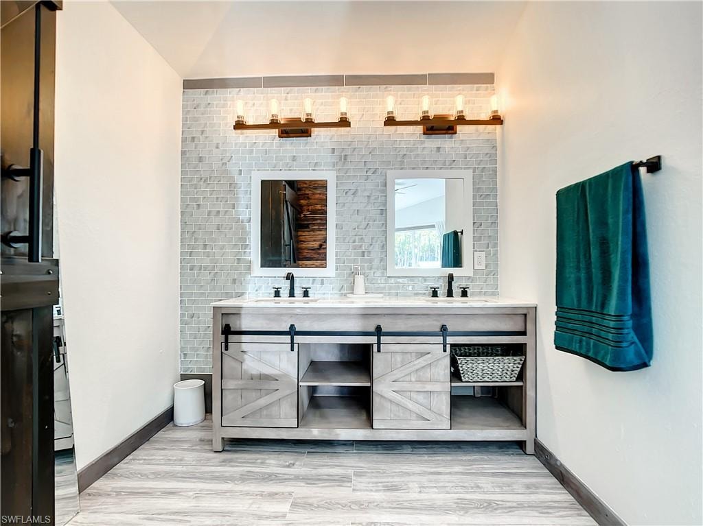 Full bathroom featuring double vanity and light wood-style floors