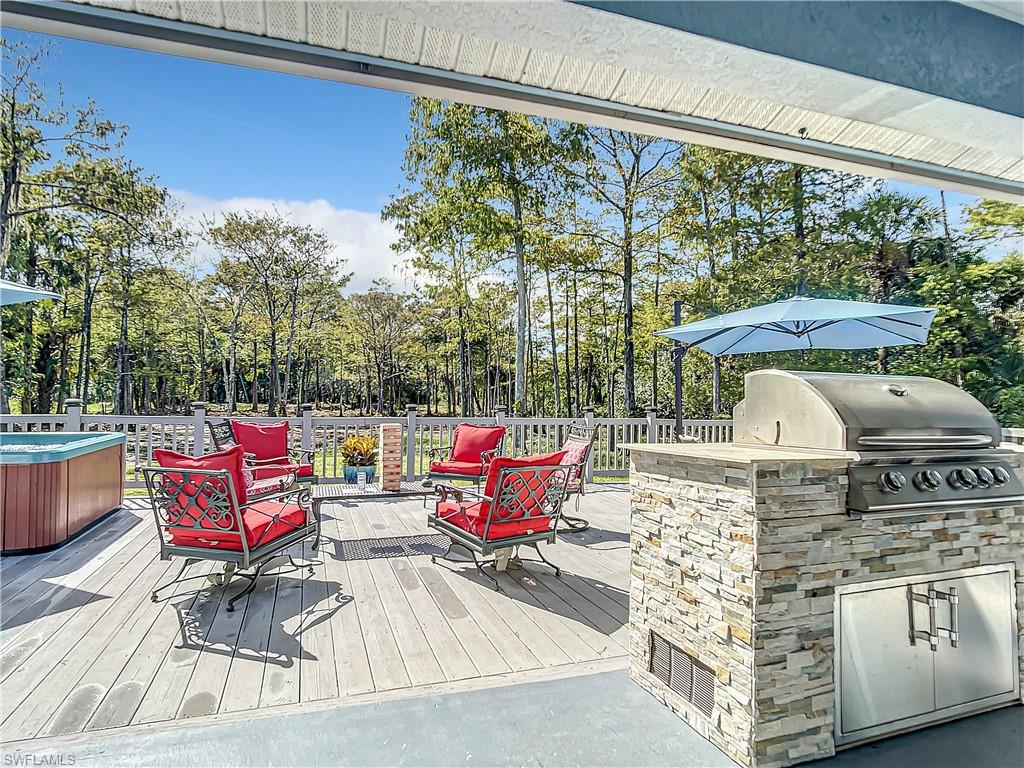 Wooden terrace with an outdoor kitchen, view of wooded area, and a hot tub