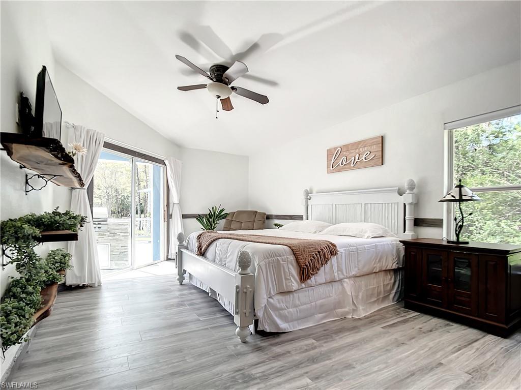 Bedroom featuring access to exterior, light wood-type flooring, vaulted ceiling, and ceiling fan