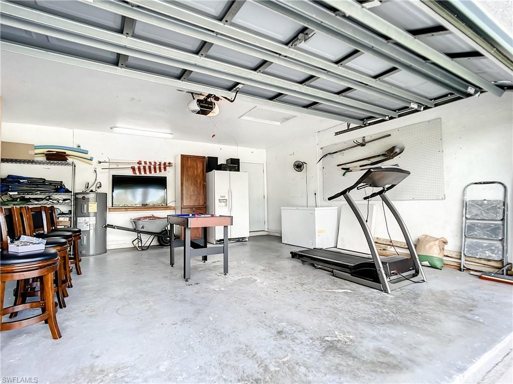 Garage featuring white refrigerator with ice dispenser, electric water heater, and white fridge