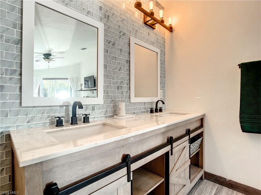 Bathroom featuring double vanity, tasteful backsplash, and a ceiling fan
