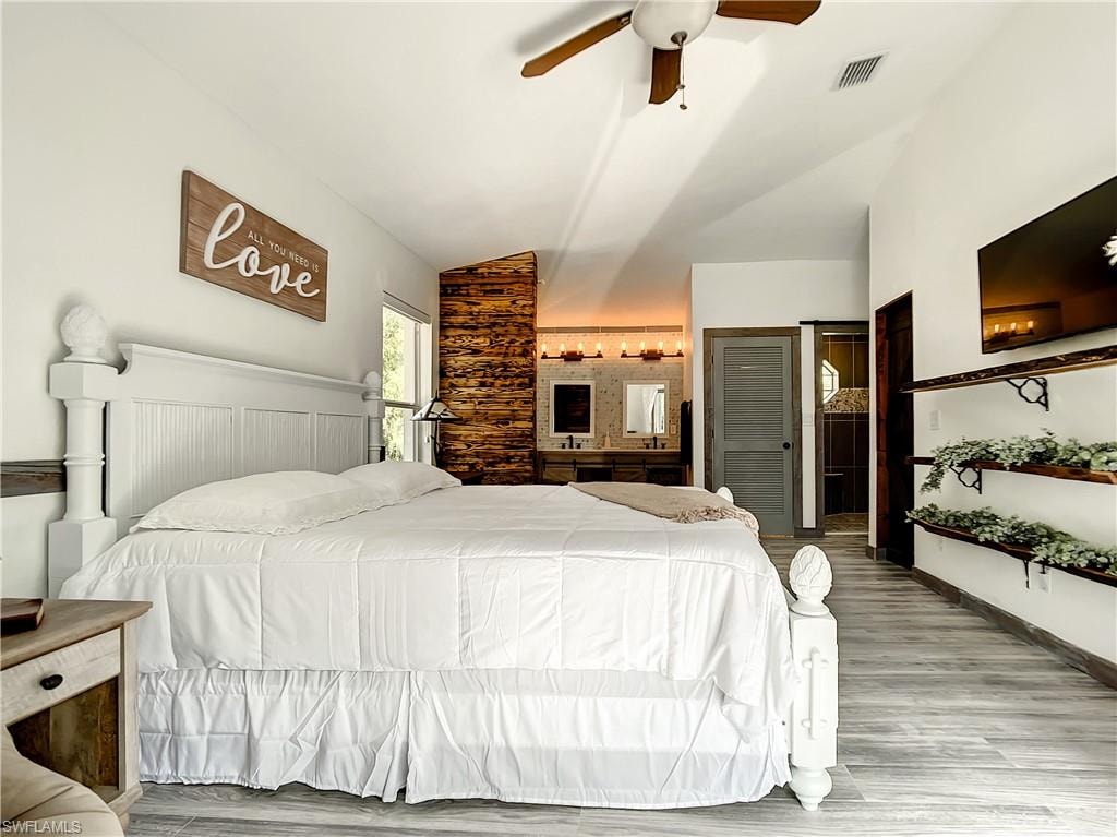 Bedroom with vaulted ceiling, light wood-type flooring, and a ceiling fan