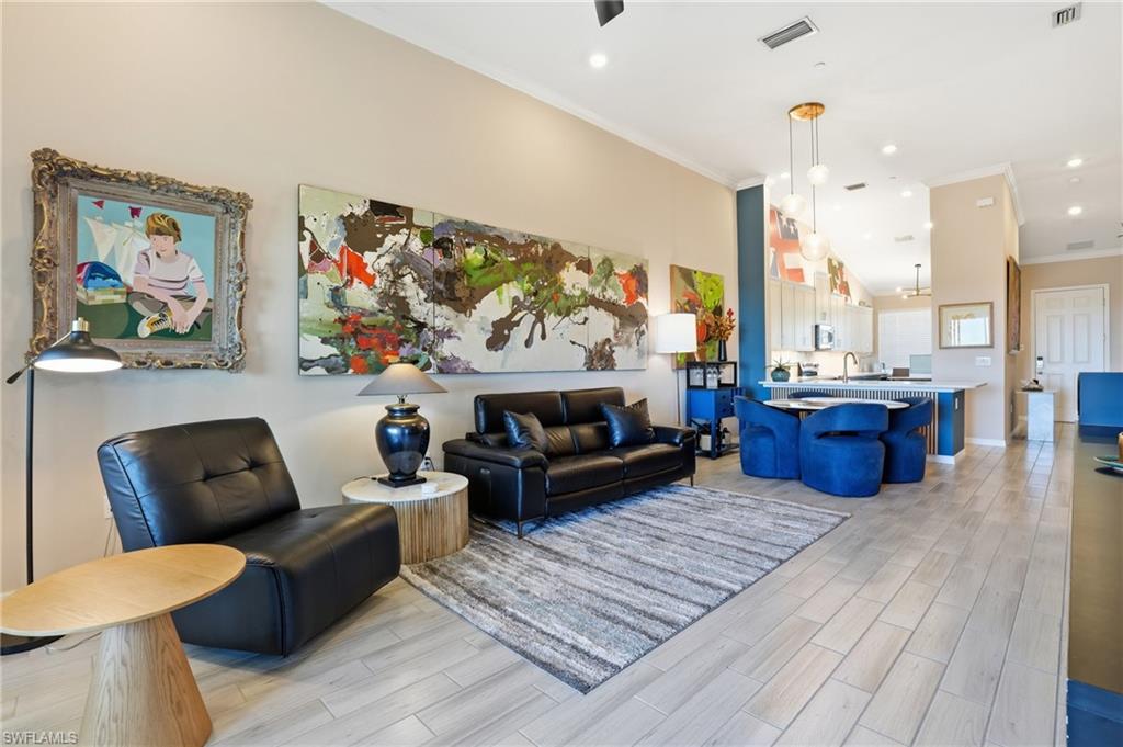 Living area featuring wood tiled floors, ornamental molding, recessed lighting, and a high ceiling