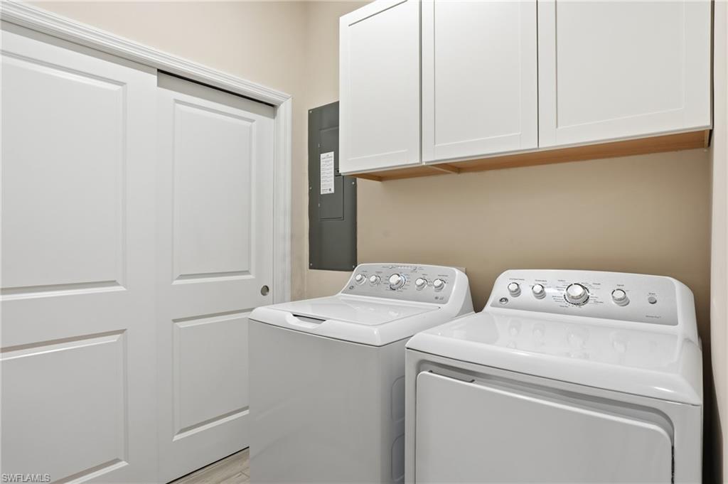 Laundry area with electric panel, washing machine and dryer, and cabinet space