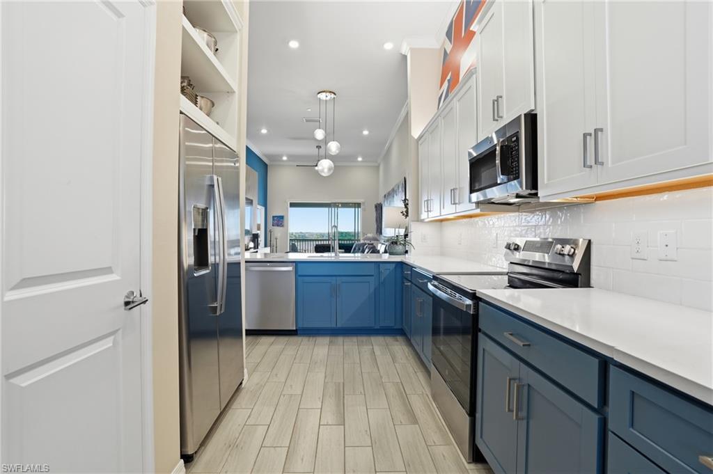 Dual tone kitchen with stainless steel appliances, decorative light fixtures, wood tiled floors, dual tone cabinets, and tasteful backsplash