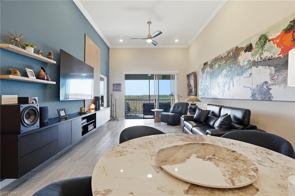 Living area featuring a ceiling fan, a high ceiling, light wood-style flooring, crown molding, and recessed lighting