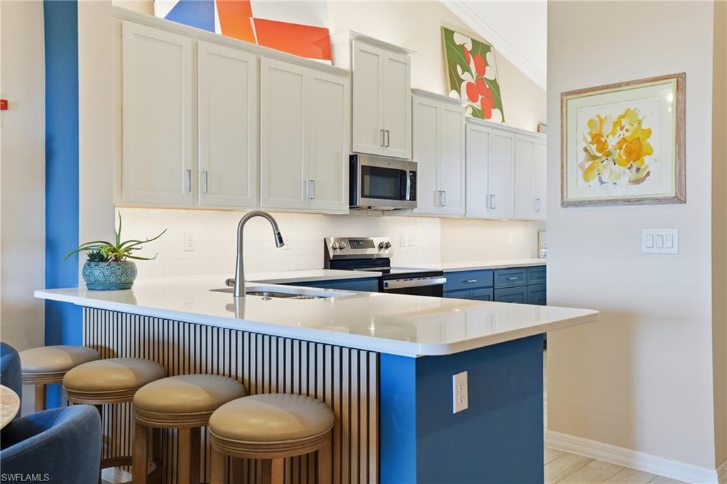 Kitchen with a breakfast bar, a peninsula, stainless steel appliances, and tasteful backsplash