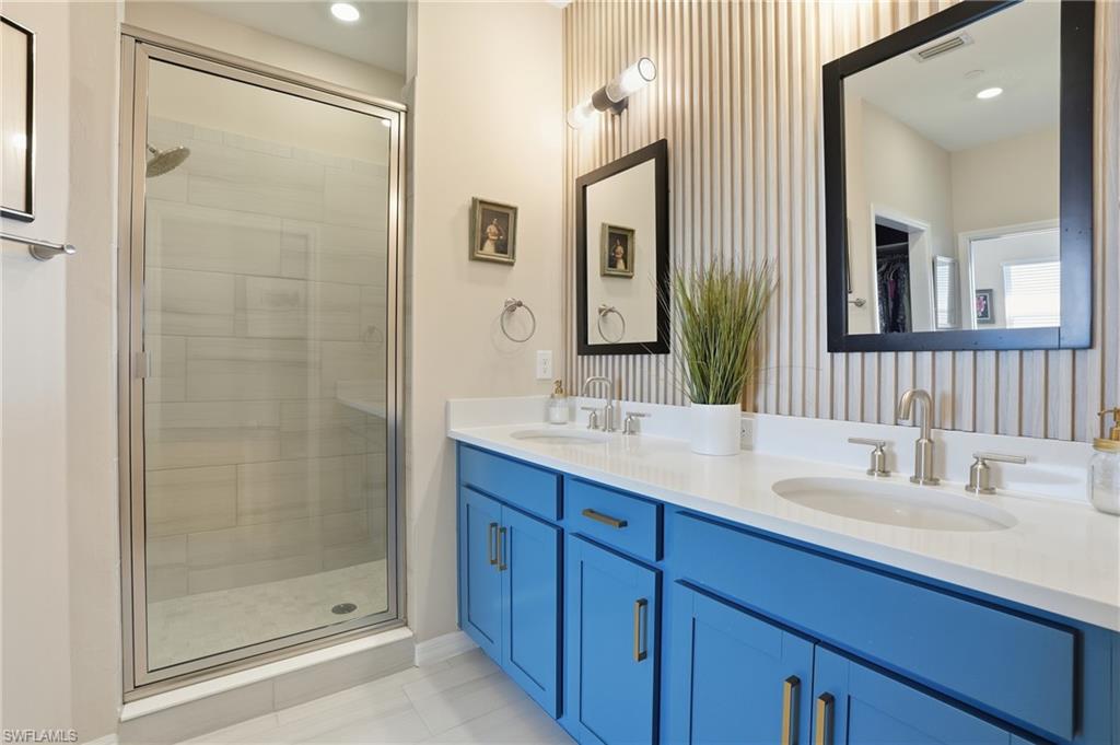Bathroom with double vanity, a shower stall, recessed lighting, light tile patterned flooring, and wallpapered walls