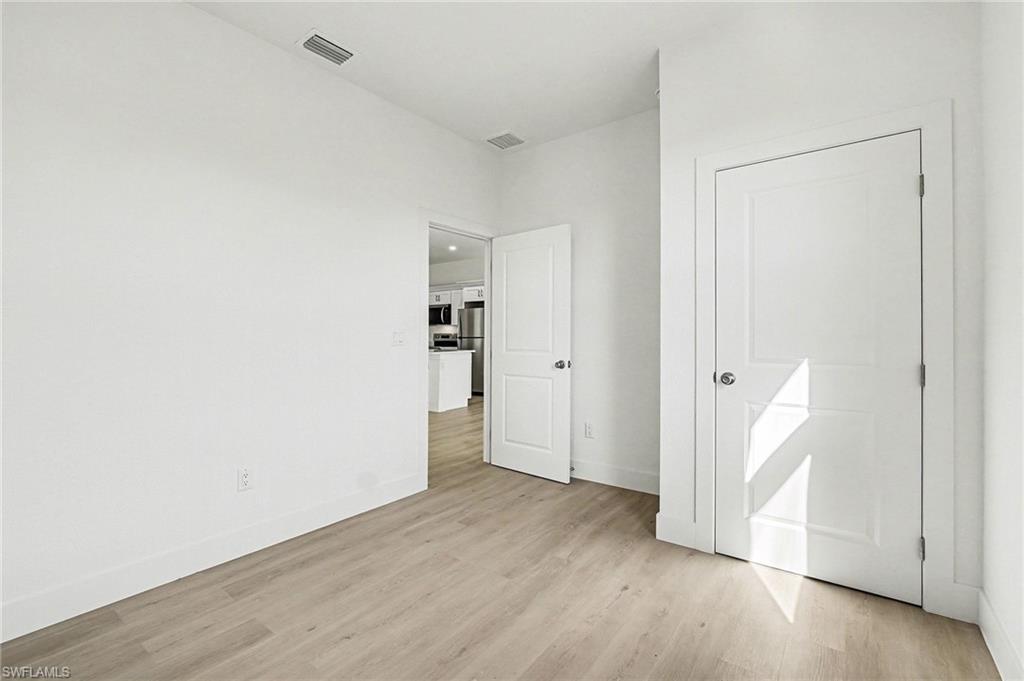 Unfurnished bedroom featuring light wood finished floors and freestanding refrigerator