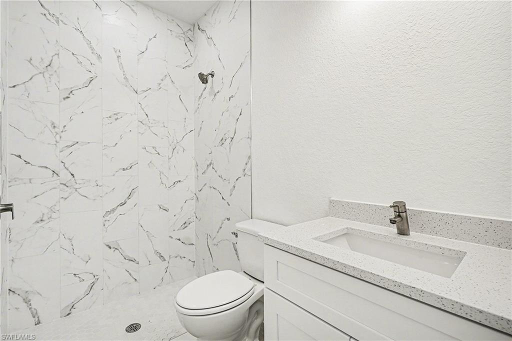 Bathroom featuring vanity, a marble finish shower, and a textured wall