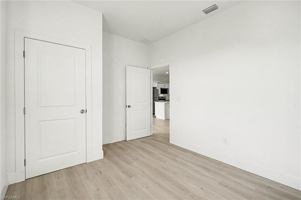 Unfurnished bedroom with light wood-style flooring and freestanding refrigerator