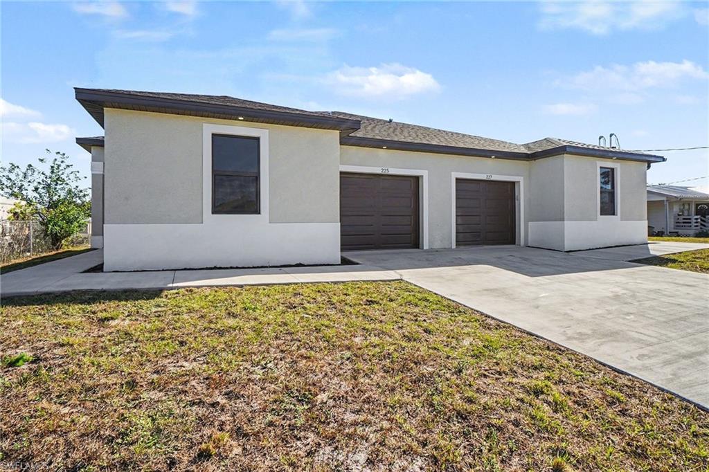 Prairie-style house with an attached garage, driveway, a front lawn, and stucco siding