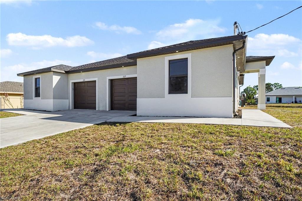 Prairie-style house featuring a garage, a front yard, concrete driveway, and stucco siding