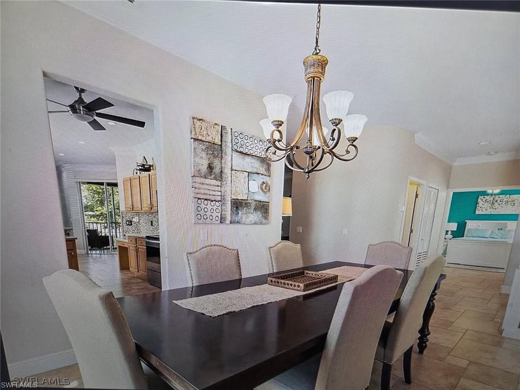 Dining space with ceiling fan, a chandelier, stone finish flooring, and crown molding