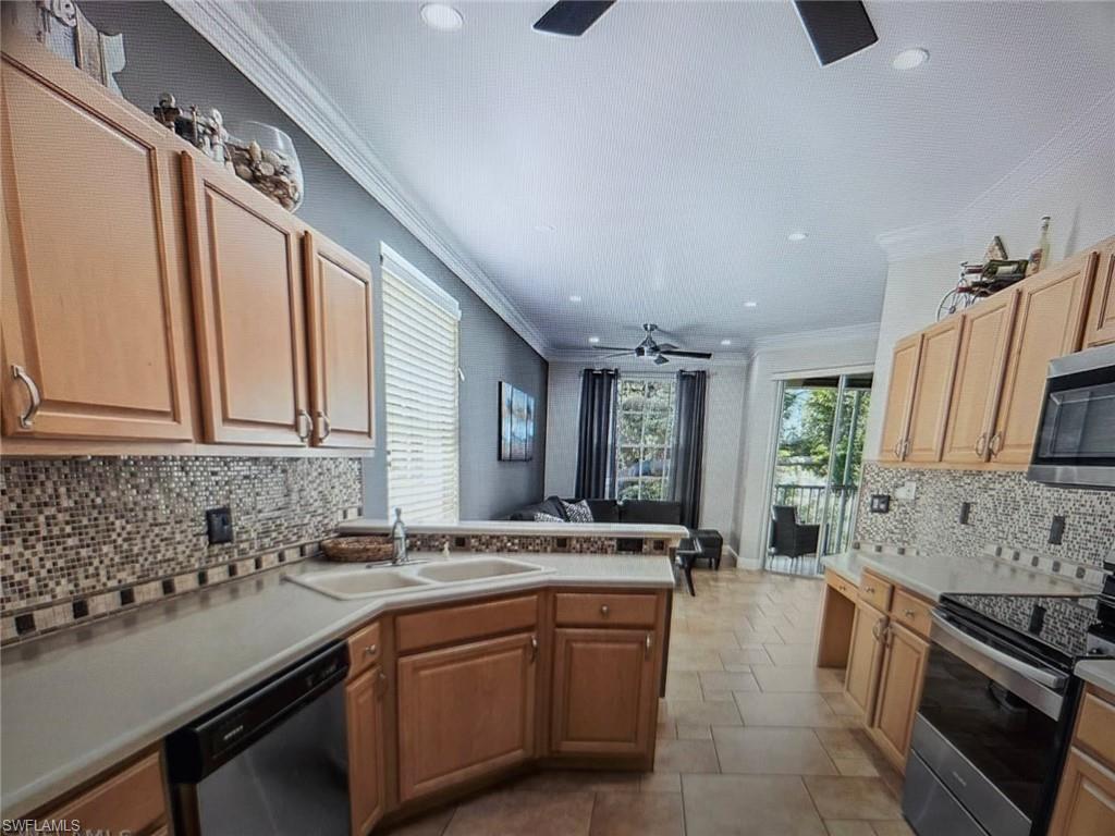 Kitchen with backsplash, a ceiling fan, stainless steel appliances, a peninsula, and light countertops