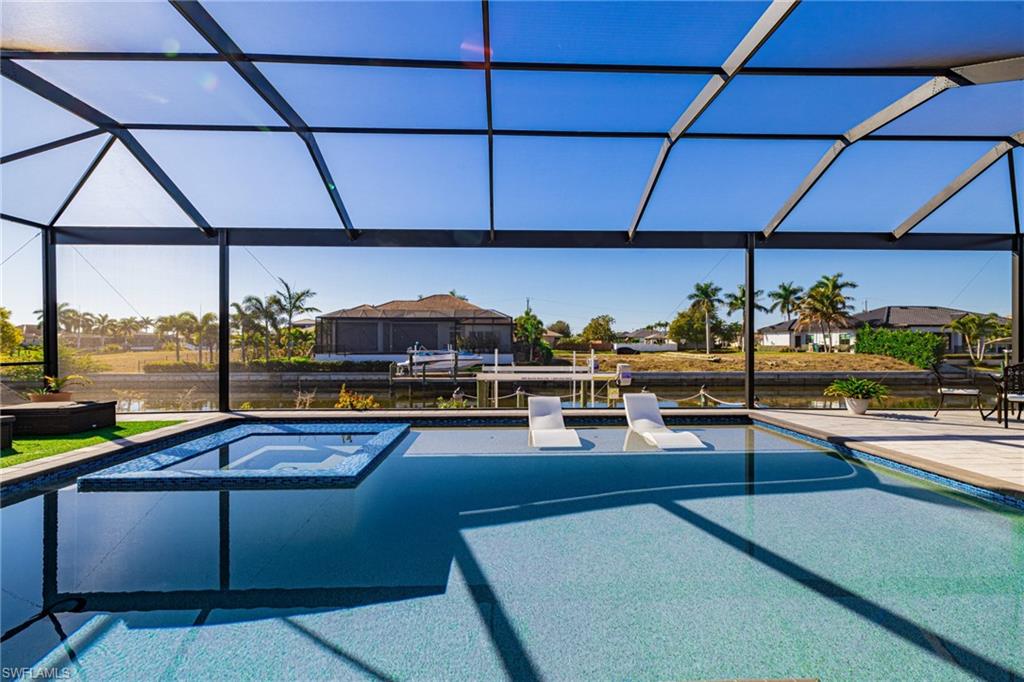 Integrated pool / spa featuring glass enclosure, a patio area, and a water view