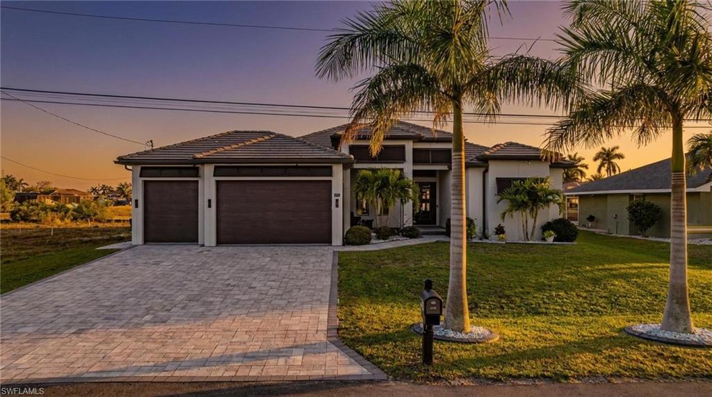 Prairie-style house with a lawn, an attached garage, decorative driveway, and a tile roof
