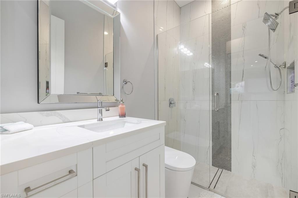 Bathroom with vanity and a marble finish shower