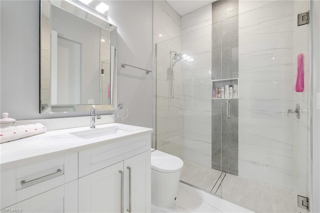 Bathroom with vanity and a marble finish shower