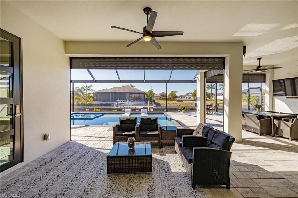 View of patio / terrace with a sunroom, a ceiling fan, glass enclosure, a pool with connected hot tub, and an outdoor living / dining area