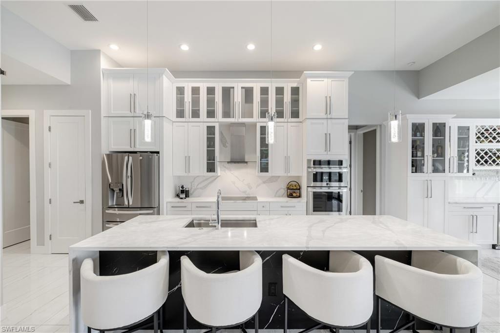Kitchen featuring glass insert cabinets, white cabinets, and light stone countertops
