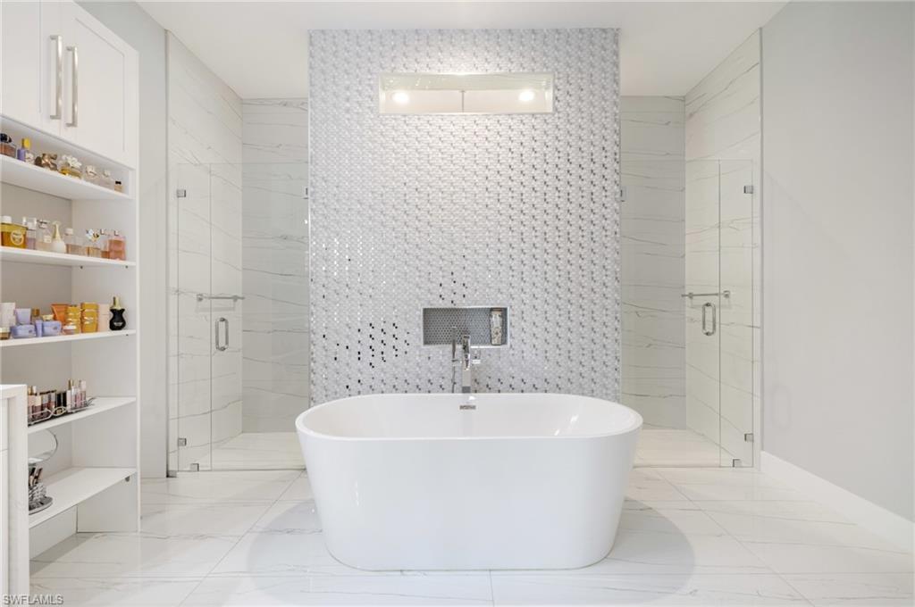 Full bathroom featuring tile walls, a marble finish shower, a soaking tub, and light marble finish floors