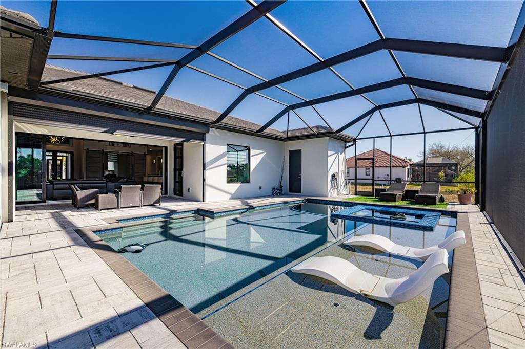 Integrated pool / hot tub featuring an outdoor hangout area, a sunroom, a patio, and glass enclosure