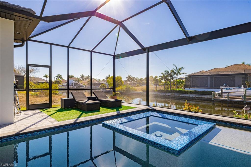 Combined pool / hot tub with a sunroom, a water view, a lanai, a patio, and a lawn
