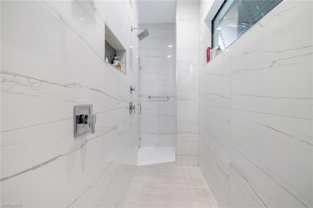 Full bath with a marble finish shower