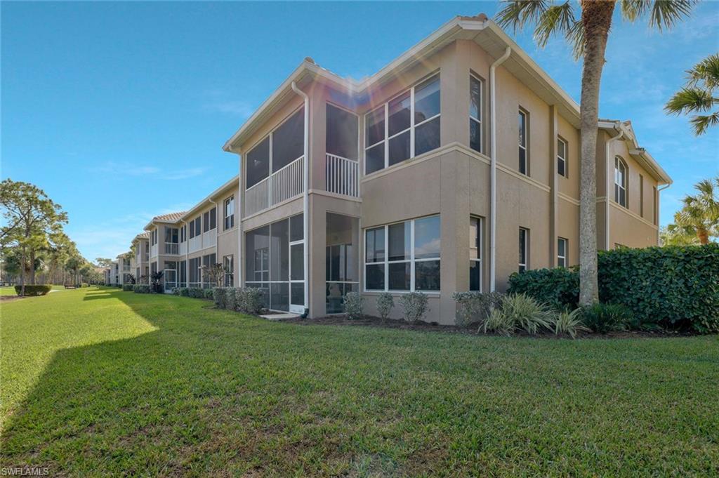 Back of property featuring a sunroom, stucco siding, a lawn, and a balcony