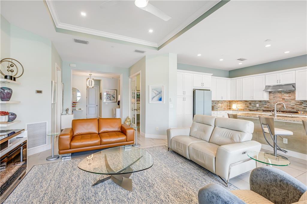 Living room featuring ceiling fan, a raised ceiling, ornamental molding, and recessed lighting
