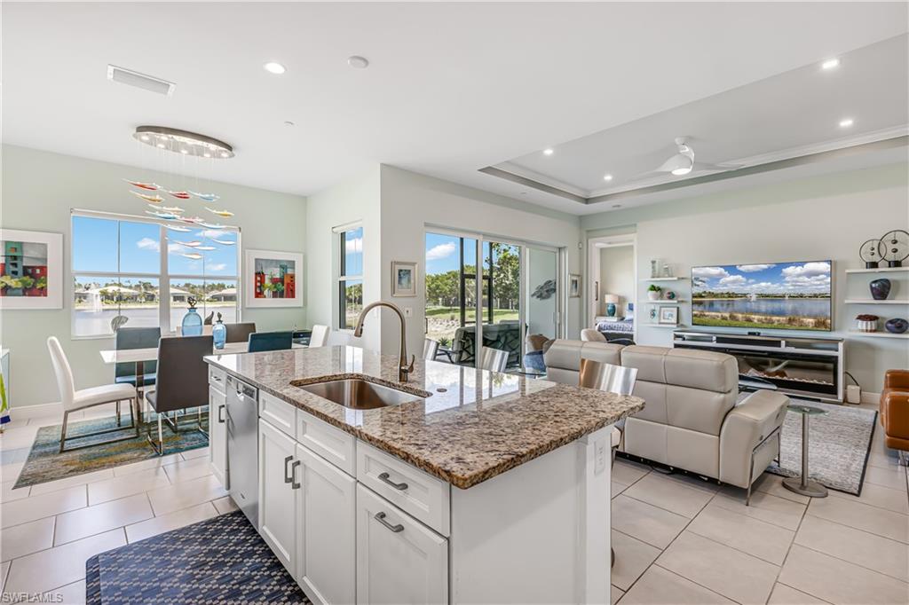 Kitchen featuring white cabinetry, light stone counters, recessed lighting, open floor plan, and a kitchen island with sink