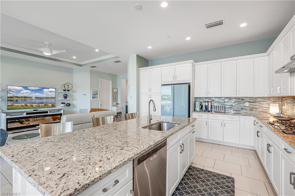 Kitchen featuring white cabinets, stainless steel appliances, ornamental molding, recessed lighting, and a raised ceiling