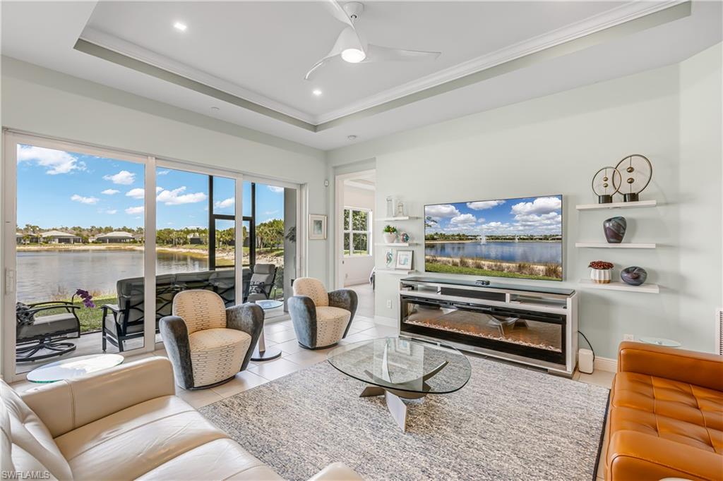 Living room featuring ceiling fan, a tray ceiling, ornamental molding, light tile patterned floors, and recessed lighting