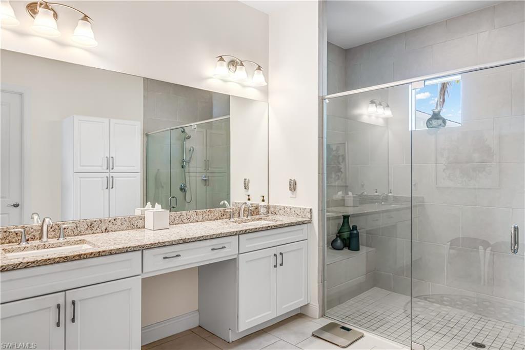 Bathroom featuring double vanity, a stall shower, and light tile patterned floors
