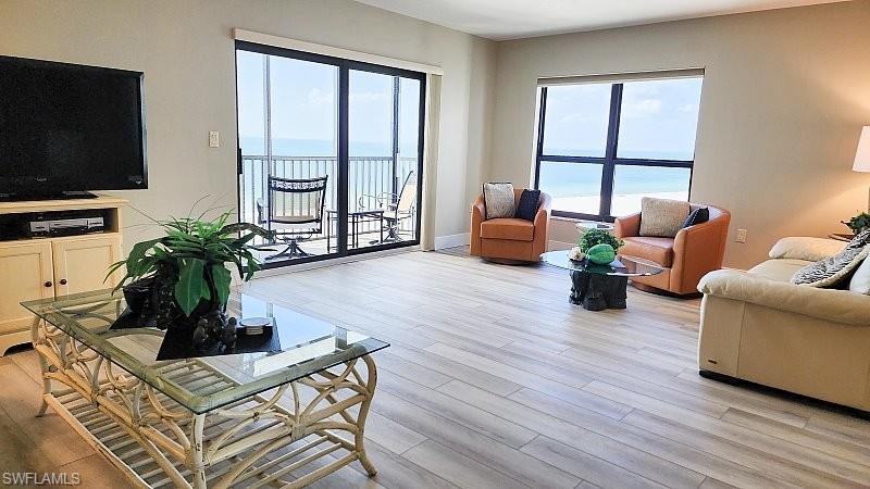 Living area featuring light wood look plank luxury vinyl floors, hurricane rated slider to beachfront balcony and large picture windows to add even more coastal natural light to this relaxing resort style beach retreat!